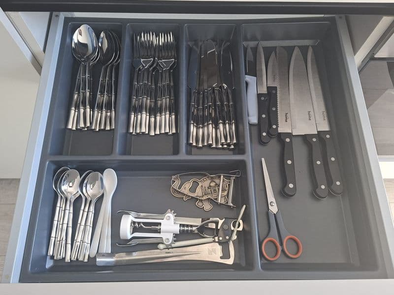 Fully equipped kitchen drawer with organized stainless steel cutlery, kitchen knives, and essential cooking utensils