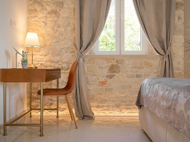 Elegant bedroom interior with stone wall and work desk-Dalmakeys